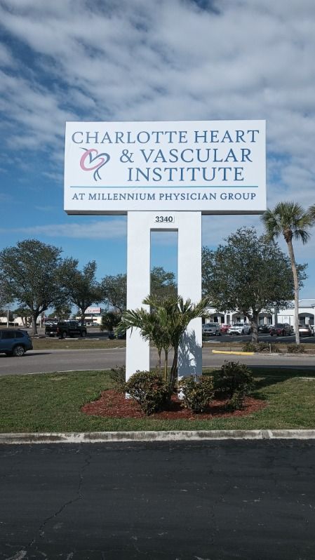 A white sign for Charlotte Heart & Vascular Institute at Millennium Physician Group, set against a blue, cloudy sky.