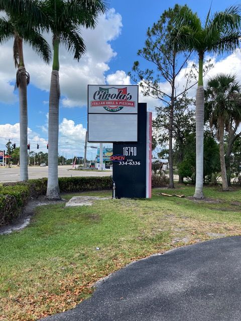 A street-level sign for Cipolla's Italian Pizzeria featuring the address 1640, set outdoors between two palm trees.