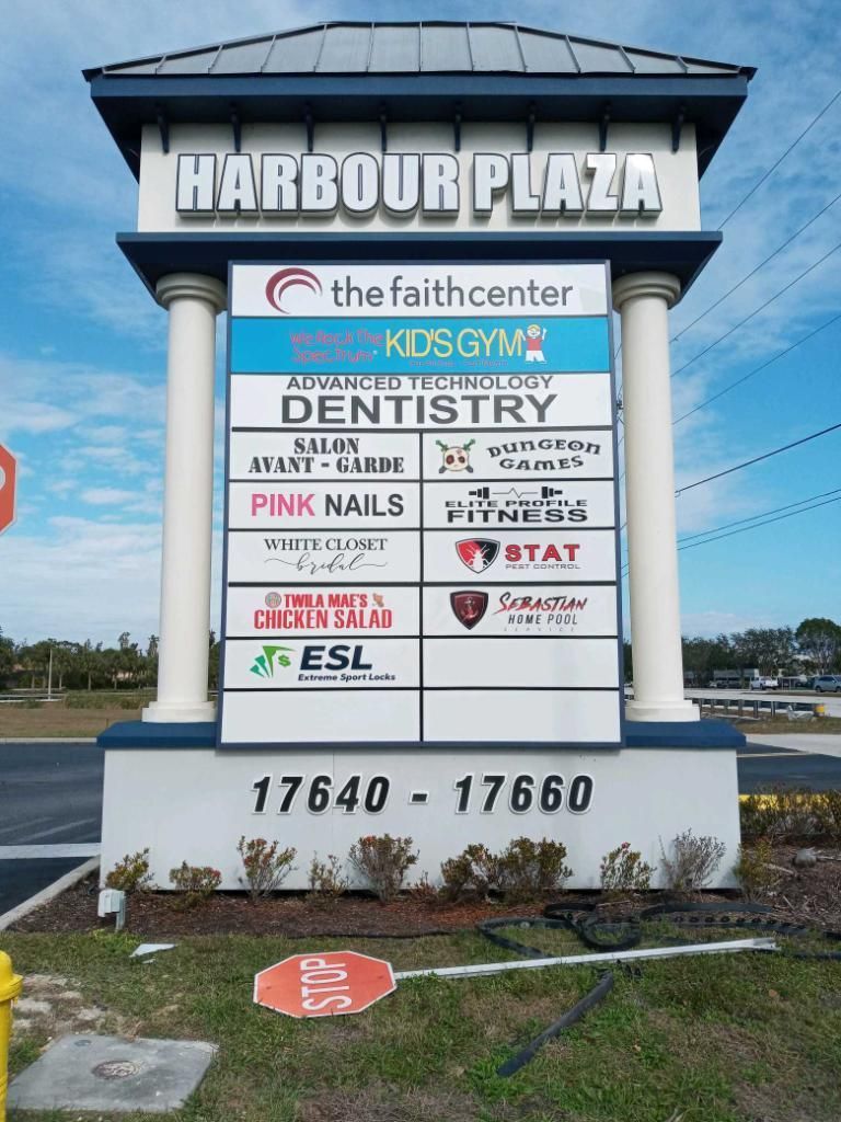 A Harbour Plaza sign featuring a list of businesses, including The Faith Center, a gym, dentist, and restaurants.