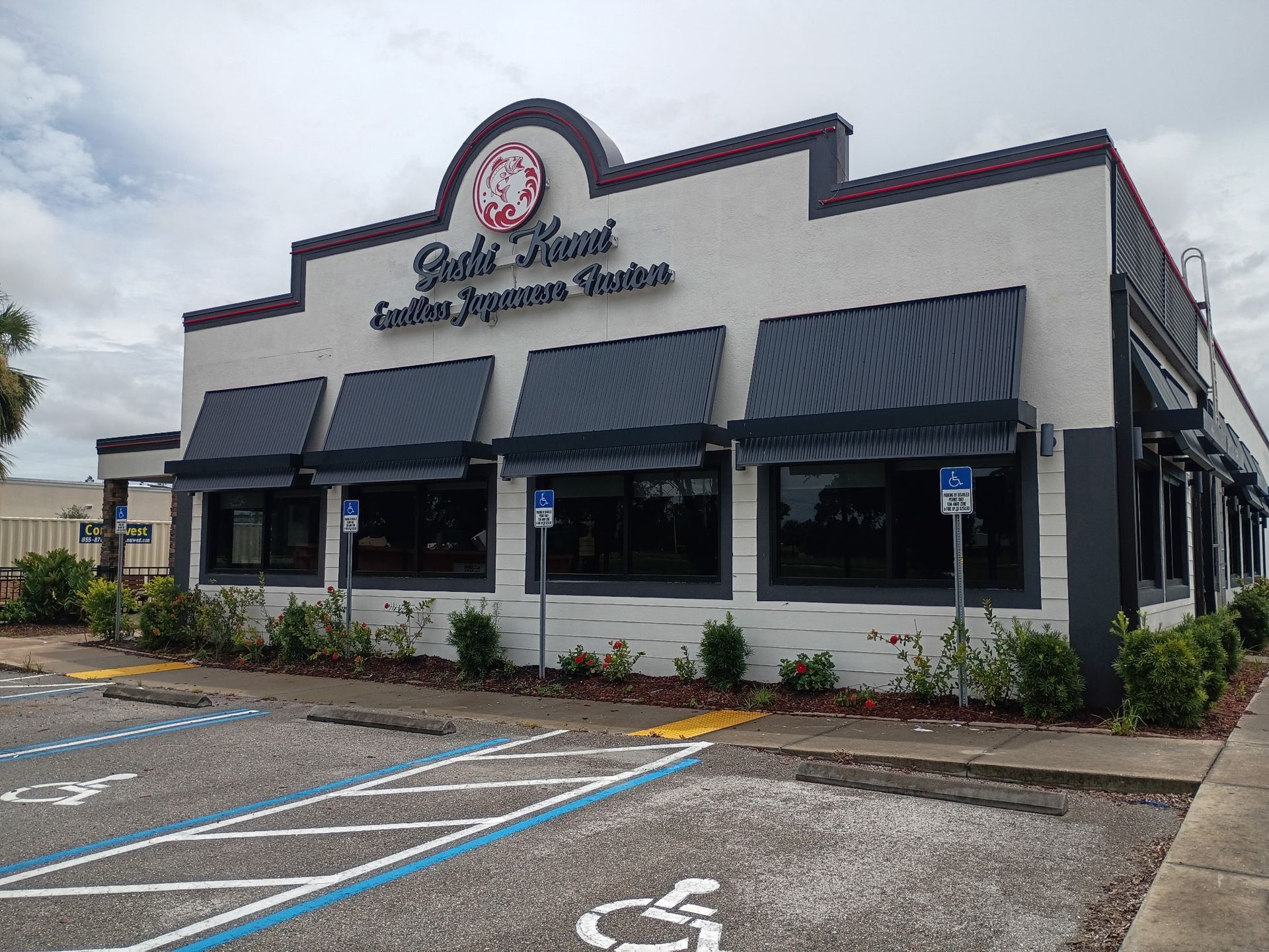 A white, one-story restaurant building named Sushi Hana with a dark roof, awnings, and handicap parking spaces in front.