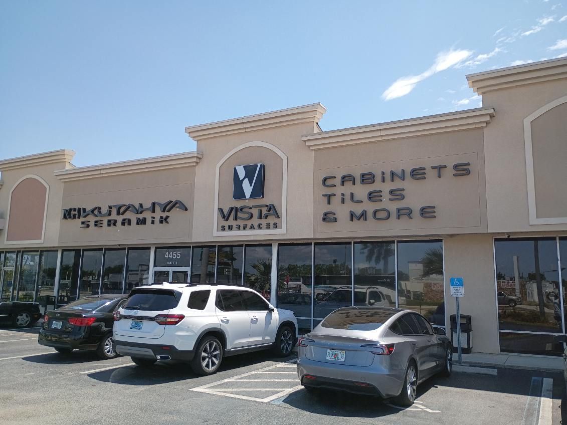 Exterior view of a Vista Remodel business storefront with parked cars in front under a clear blue sky.
