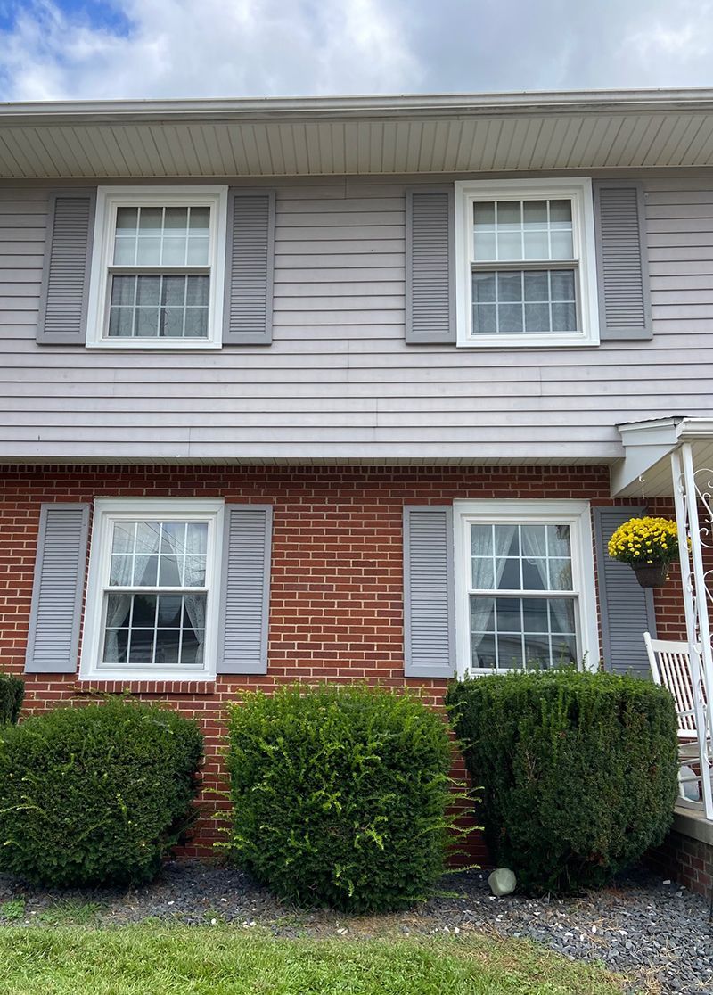 The front of a brick house with gray shutters and a porch.