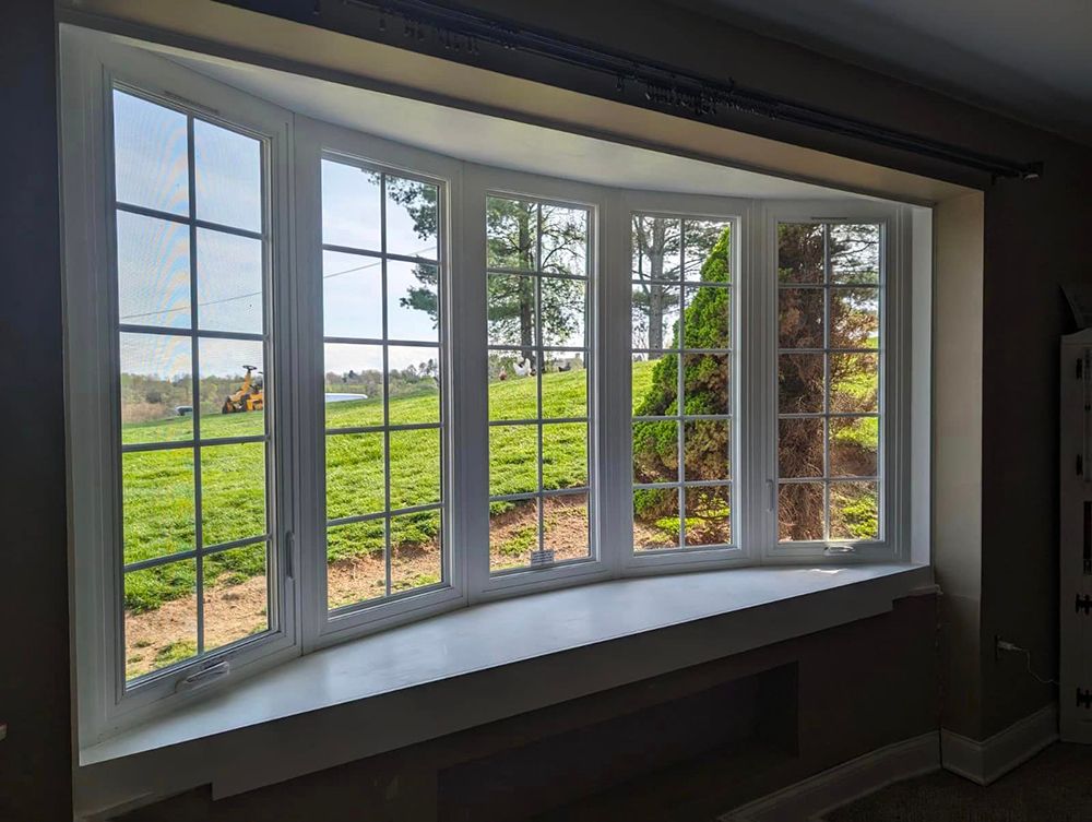 A large bay window in a living room with a view of a field.