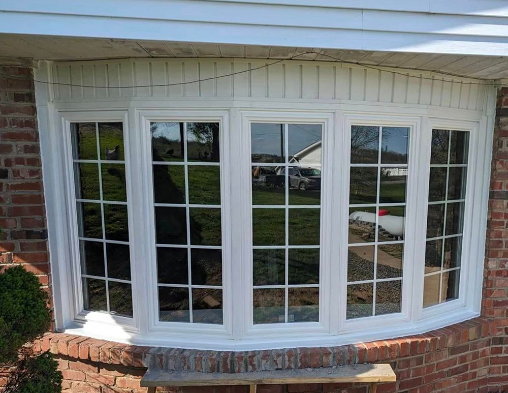 A large bay window on the side of a brick house.