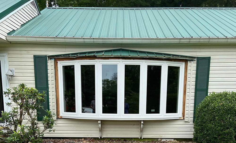 A house with a green roof and a large window.
