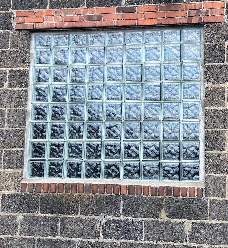 A brick wall with a window made of glass blocks