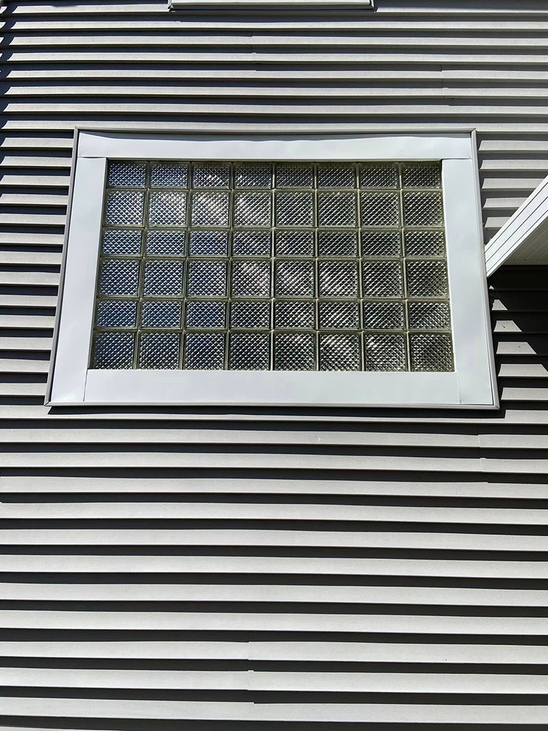 A window on the side of a house with a glass block window.