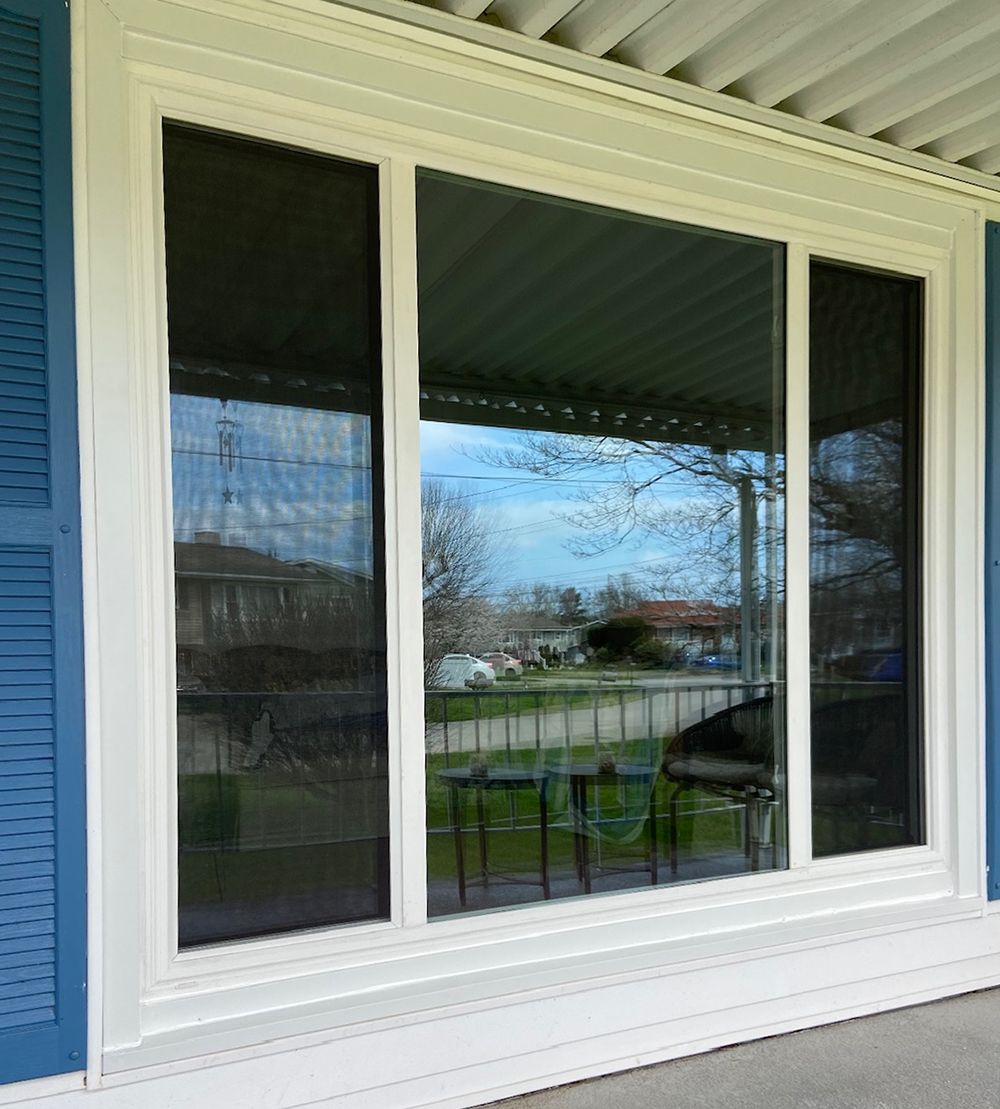 A white window with blue shutters on a porch.