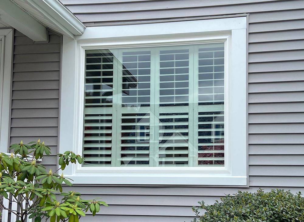 A window with shutters on it is on the side of a house.