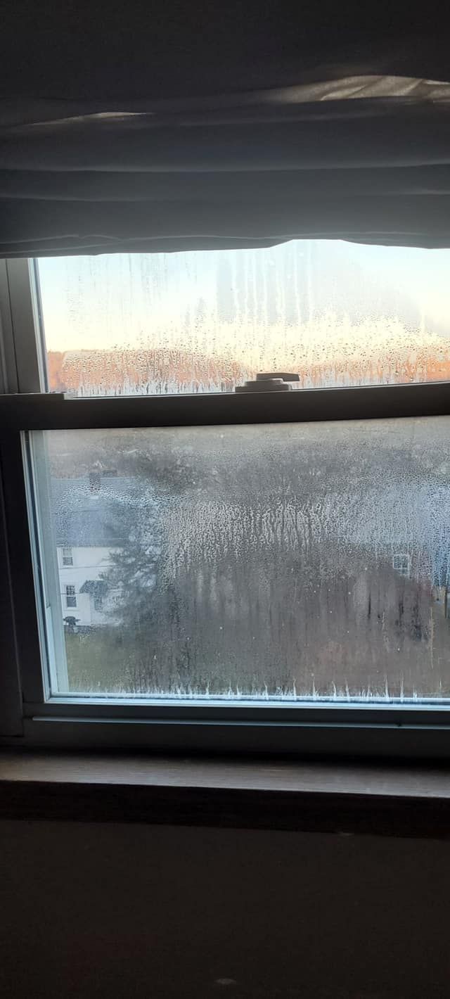 A window with a lot of condensation on it and a view of a field.
