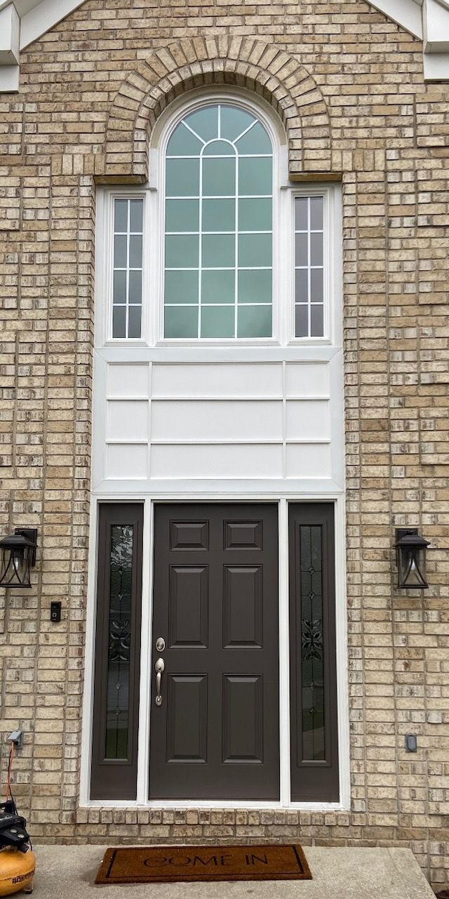 The front door of a brick house with a large window.