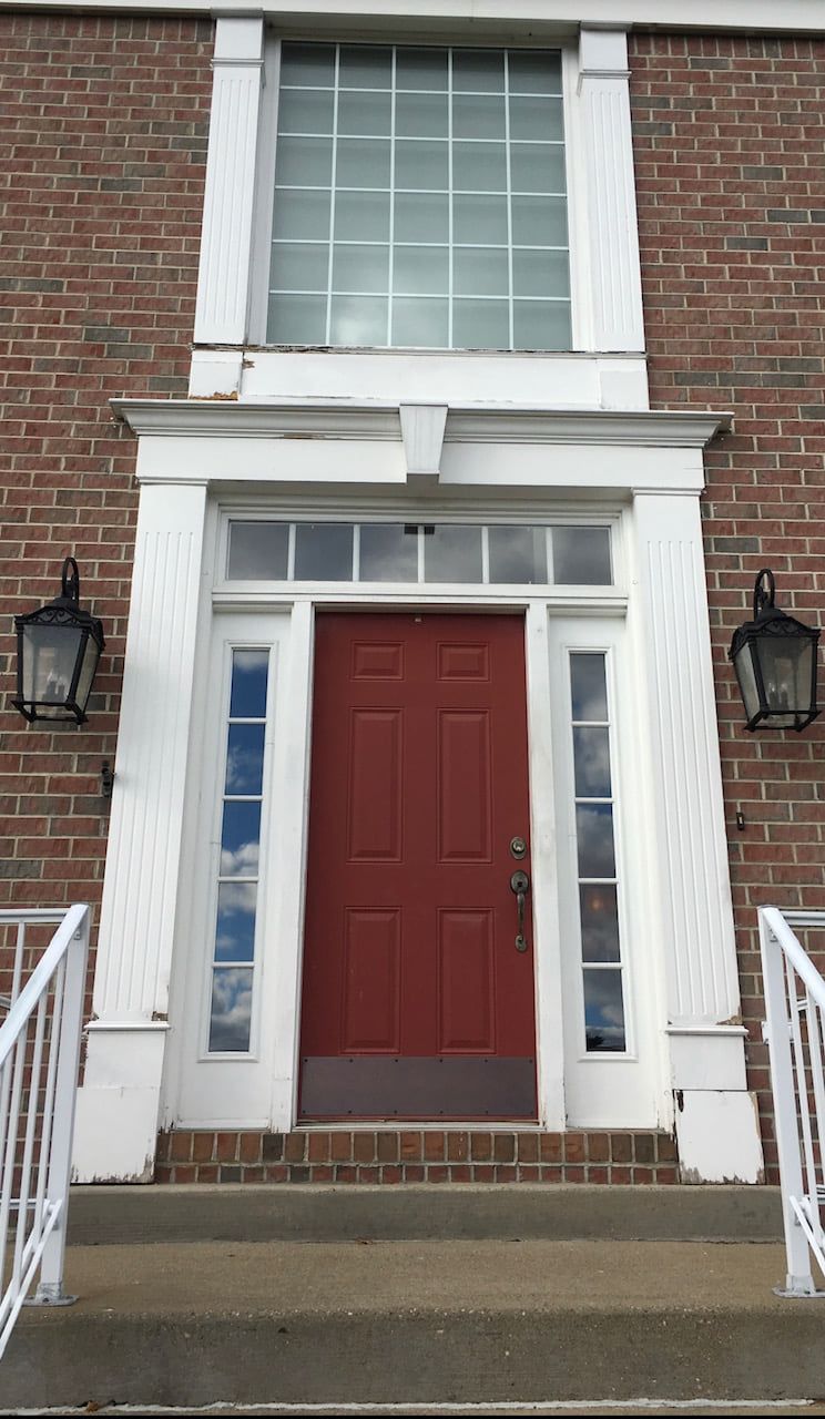 A brick building with a red door and white trim