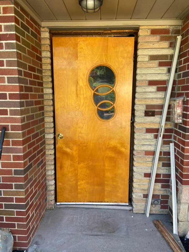 A wooden door with a round window in a brick building.