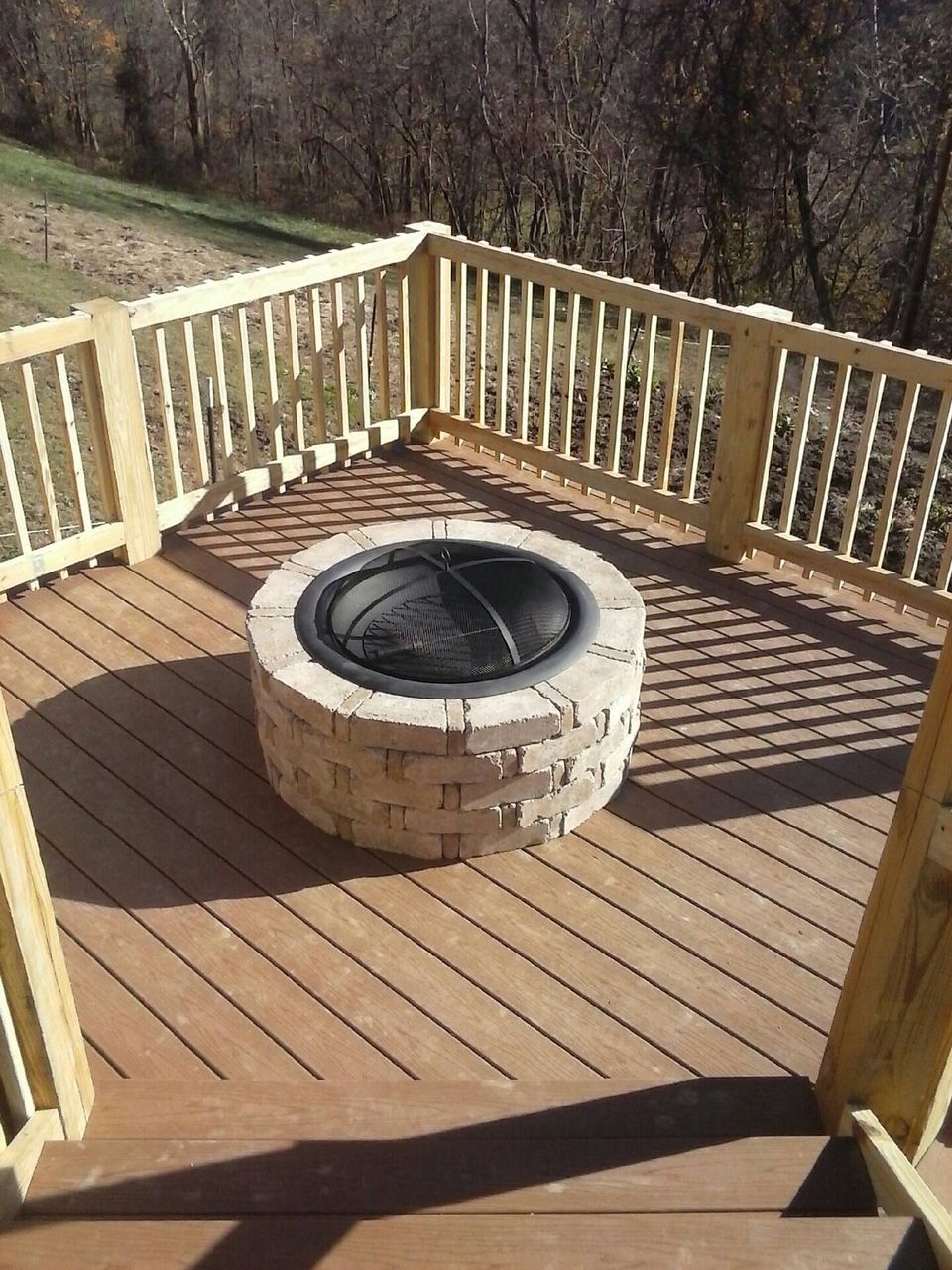 A wooden deck with a fire pit in the middle