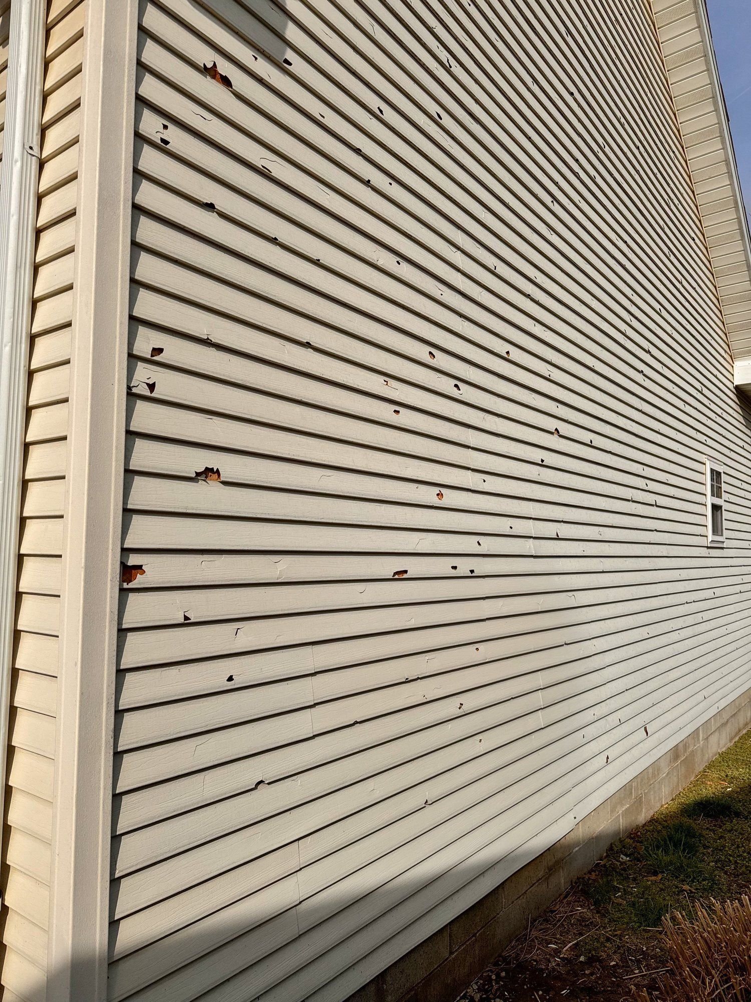 Closed white metal roll-up shutter on a beige building wall, viewed at an angle.