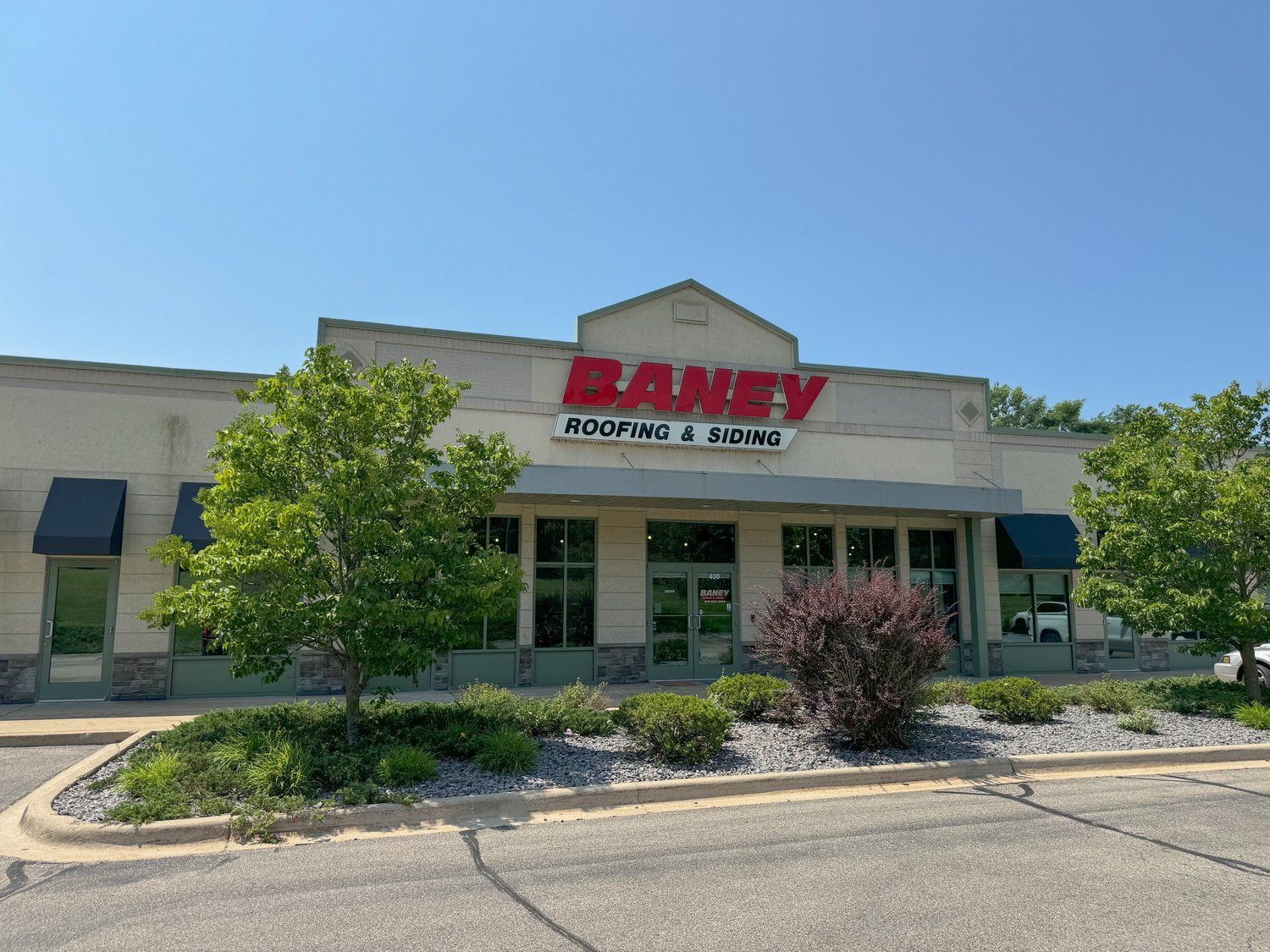 Exterior of a Bane furniture and living store with glass storefront and landscaping under a clear blue sky