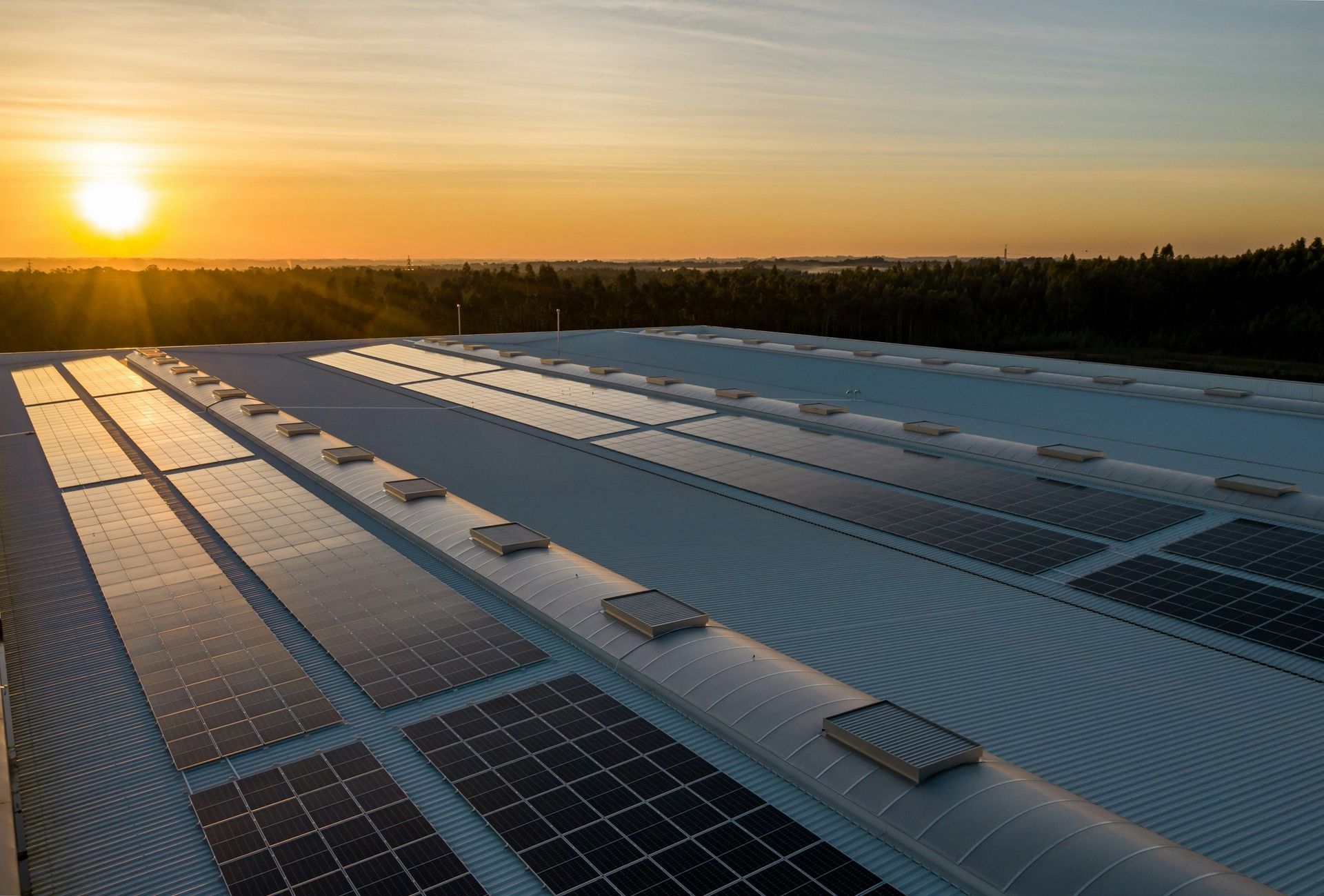 Sunset over a large rooftop covered with solar panels and vents