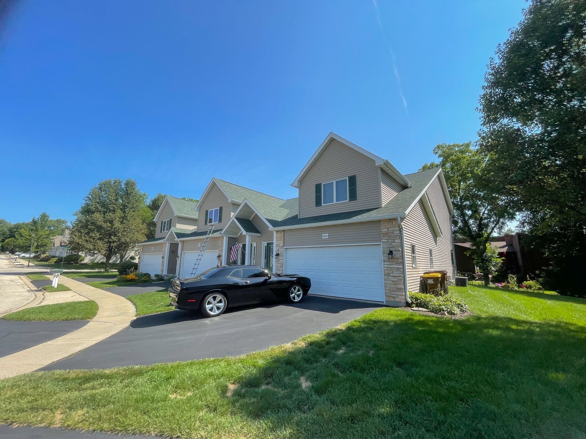 Suburban house with a black SUV parked in the driveway on a sunny day