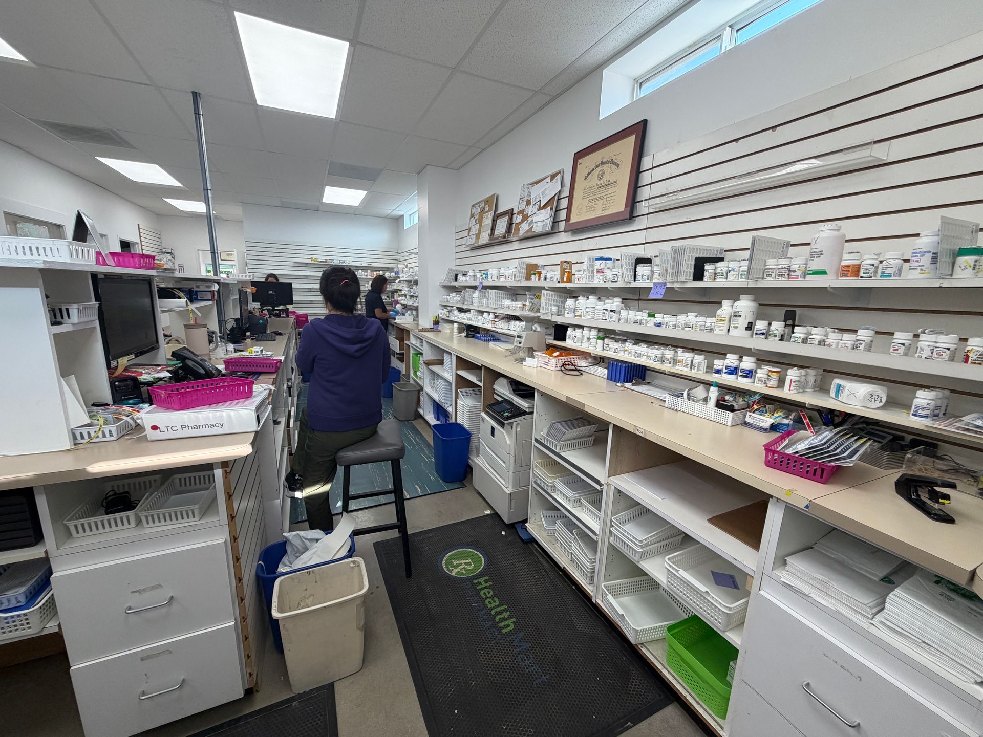 Person in a white aisle-lined store with shelves of packaged goods and a blue bucket on the floor.