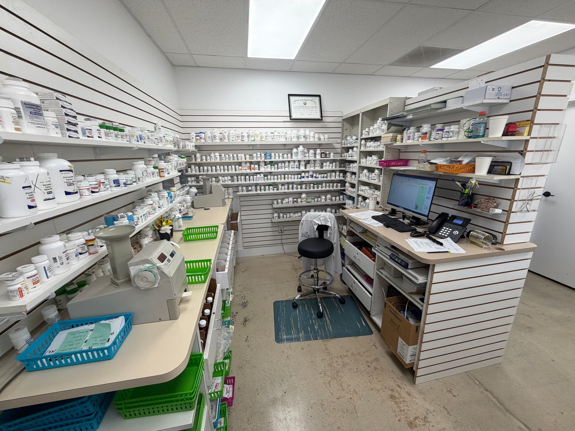 Pharmacy interior with shelves of medicine, a counter, and a computer workstation