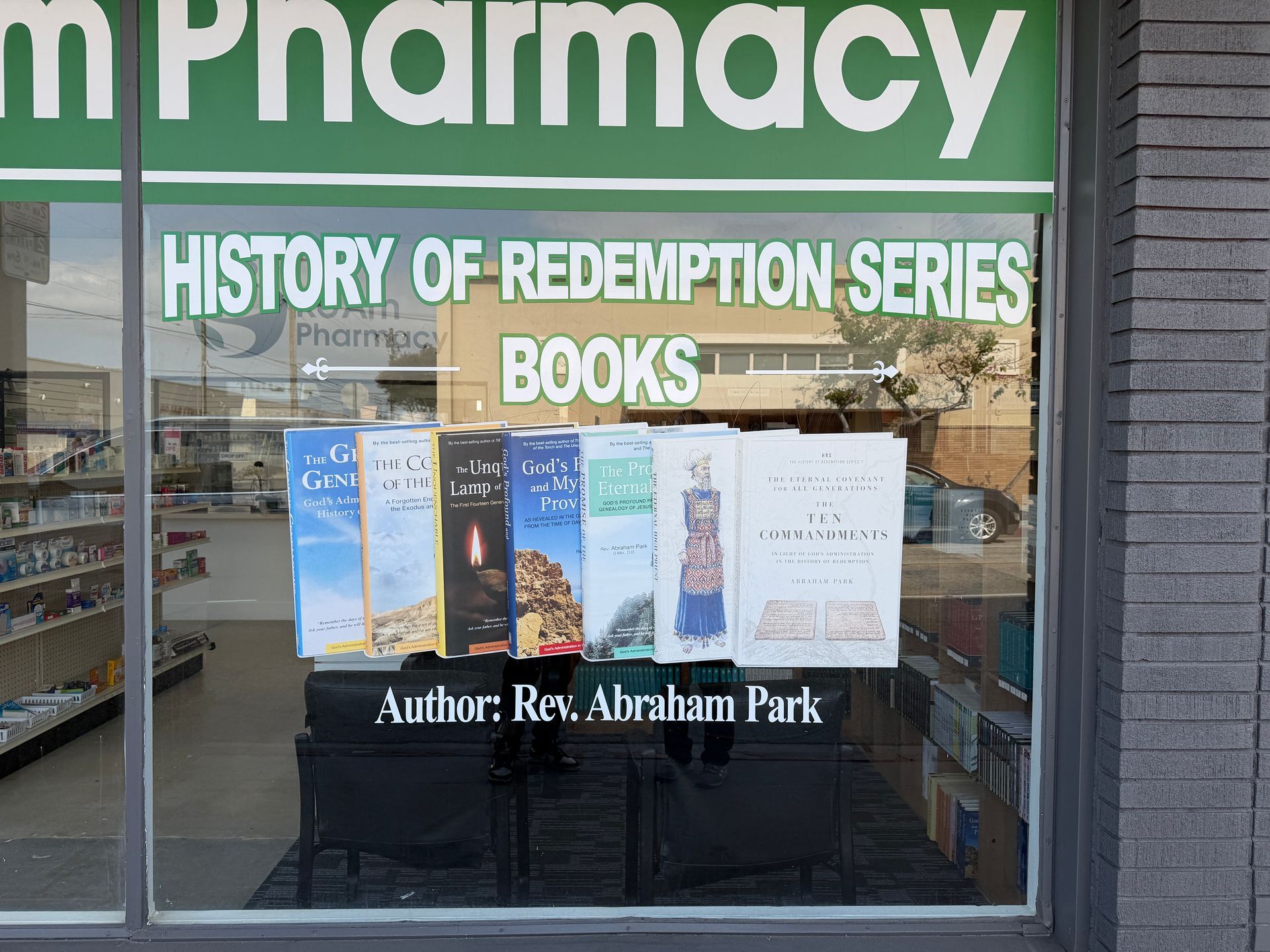 Pharmacy storefront window display advertising “History of Redemption Series” books by Rev. Abraham Park