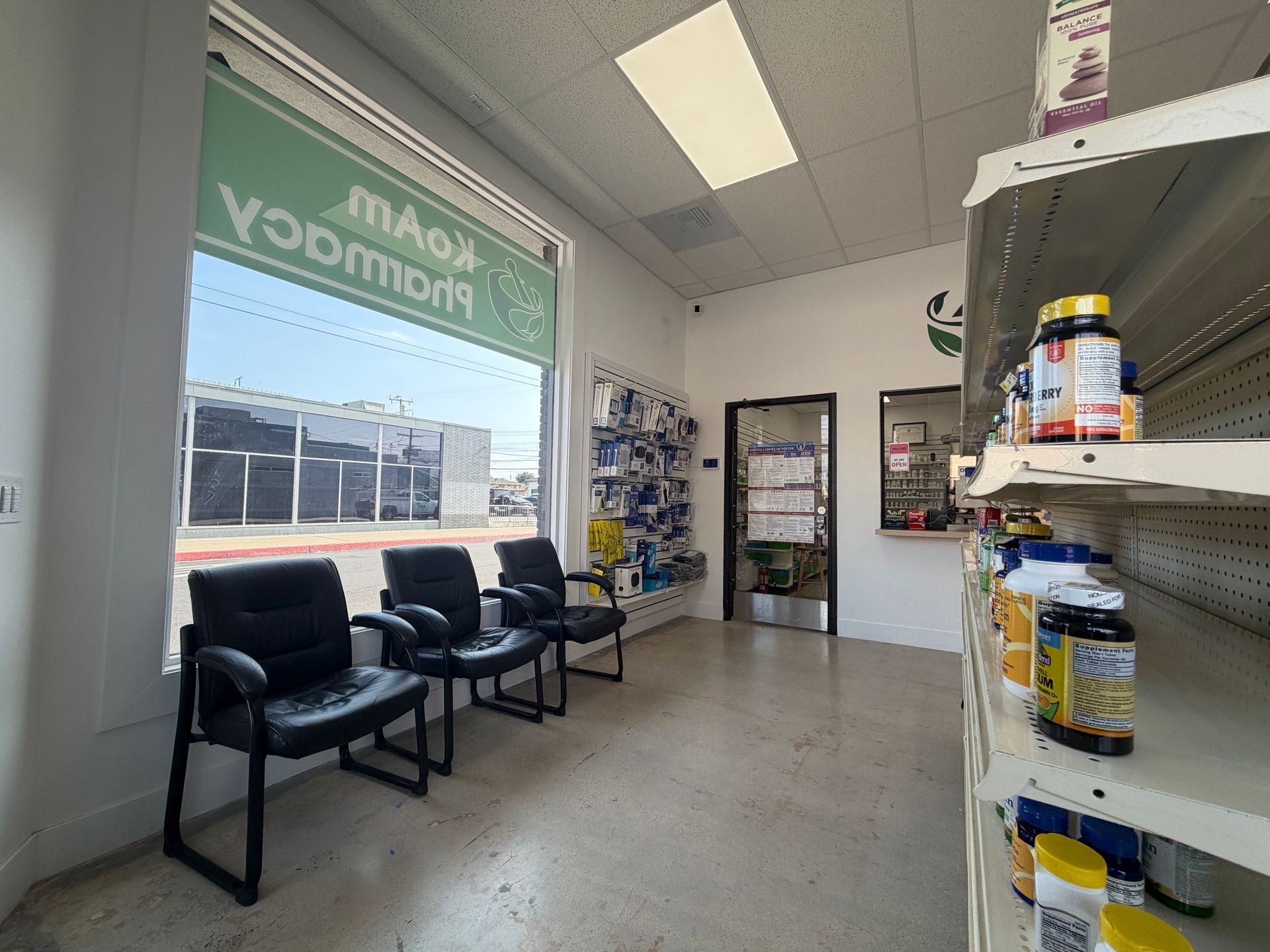 Small shop waiting area with chairs, shelves of snacks, and a front window with mirrored lettering