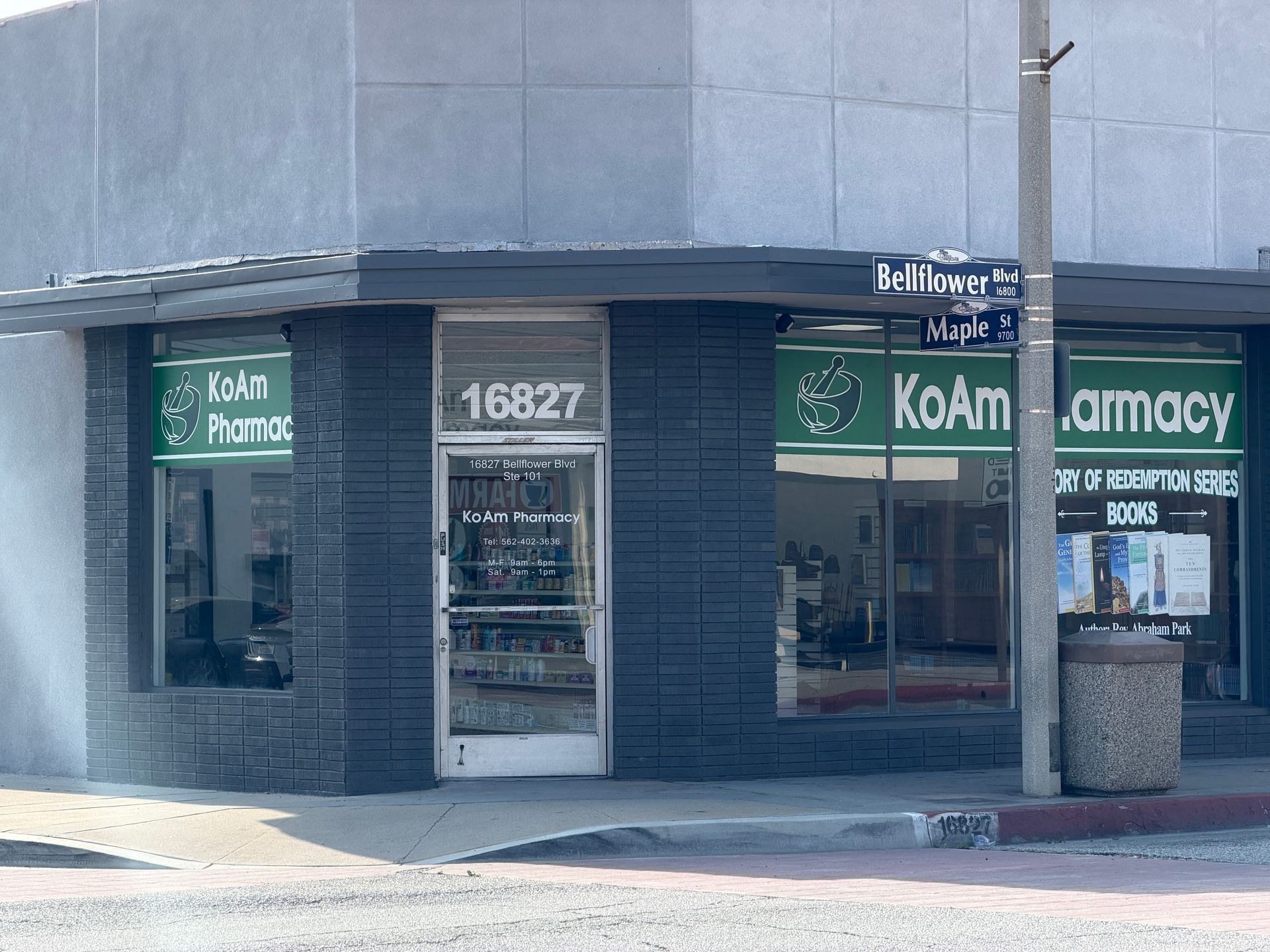 Corner storefront with Koam pharmacy sign and address 16827, blue-gray exterior on a city street