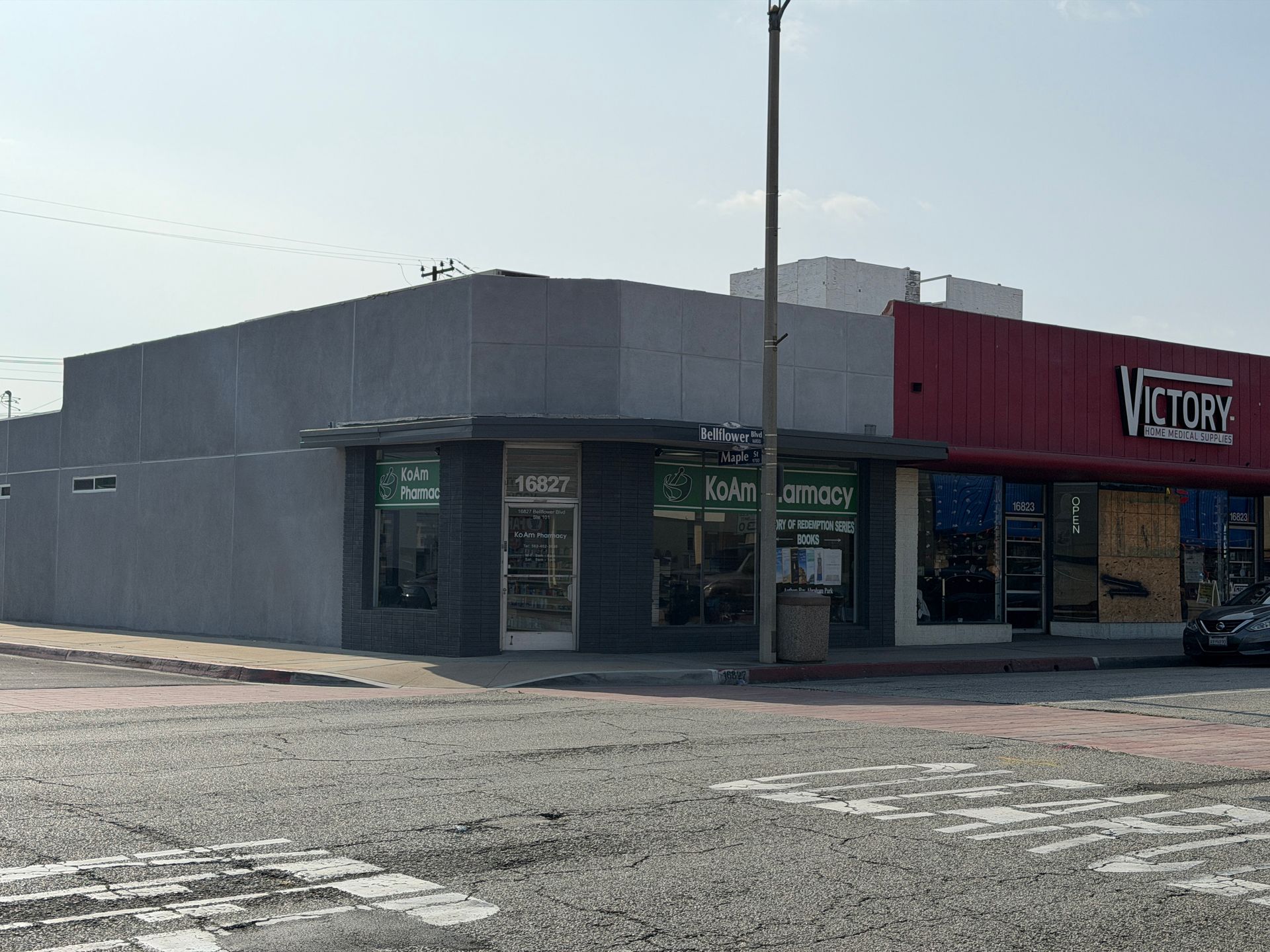 Street corner view of a gray and red storefront with glass windows and a red sign reading “Victor.”