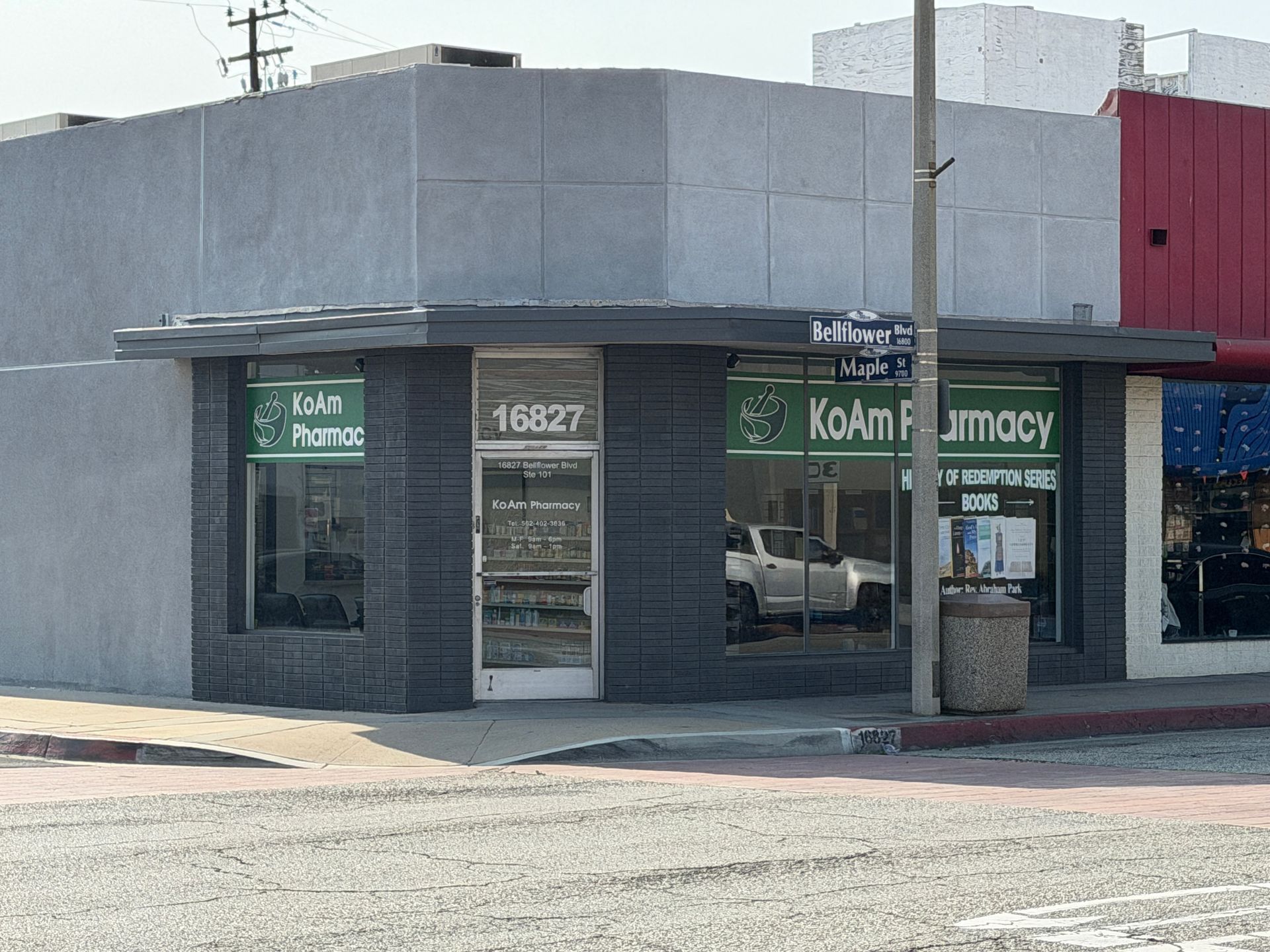 Corner storefront for a pharmacy with green signage and a glass door on a city street.