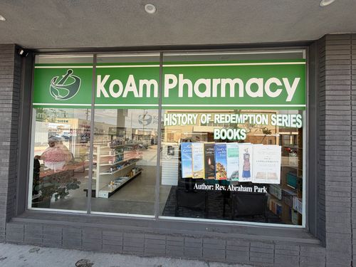 KoAm Pharmacy storefront with green sign and window display of prescription books