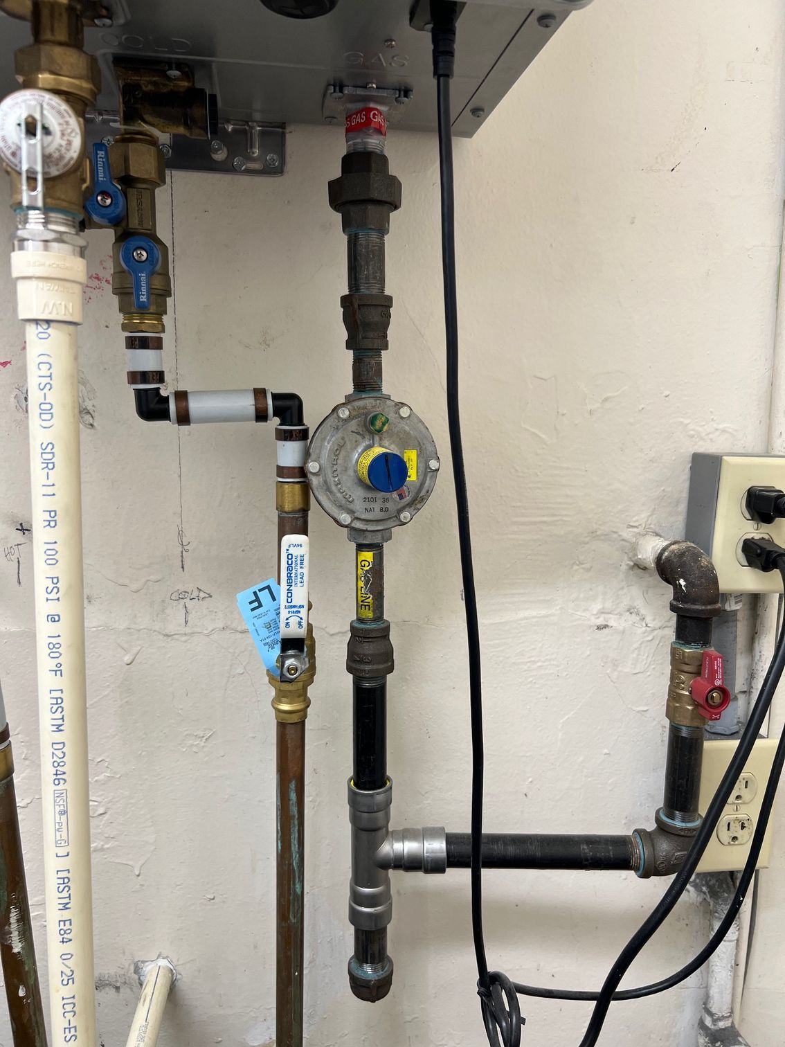 Gas regulator and associated pipes and valves mounted on a wall.