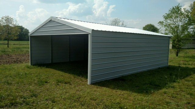 Gray metal carport on grass, with a white roof, under a blue sky.
