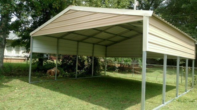 Tan metal carport on green grass.