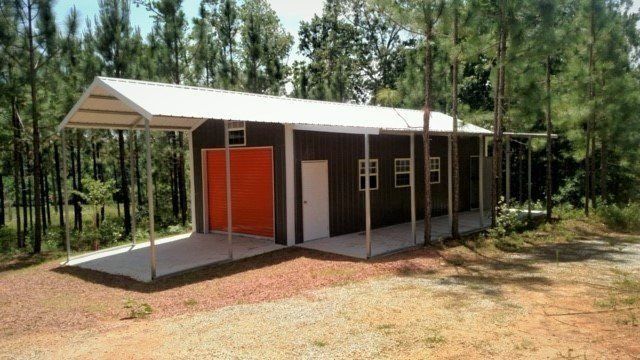 Metal building with carport, orange door, white trim, in a wooded area.