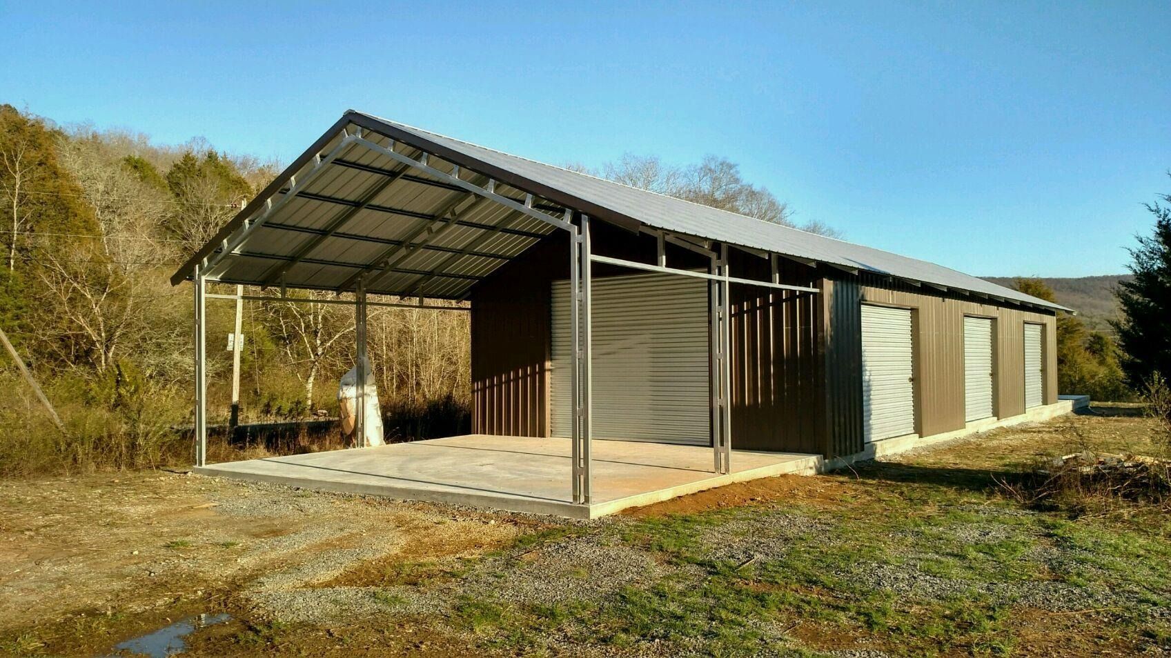 Metal-framed storage shed with open awning, set on a concrete pad with a gravel ground, brown walls, and a blue sky.
