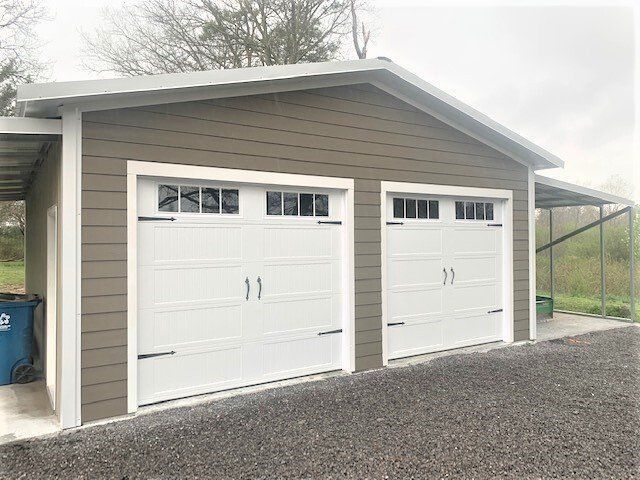 Tan garage with white doors and a carport.