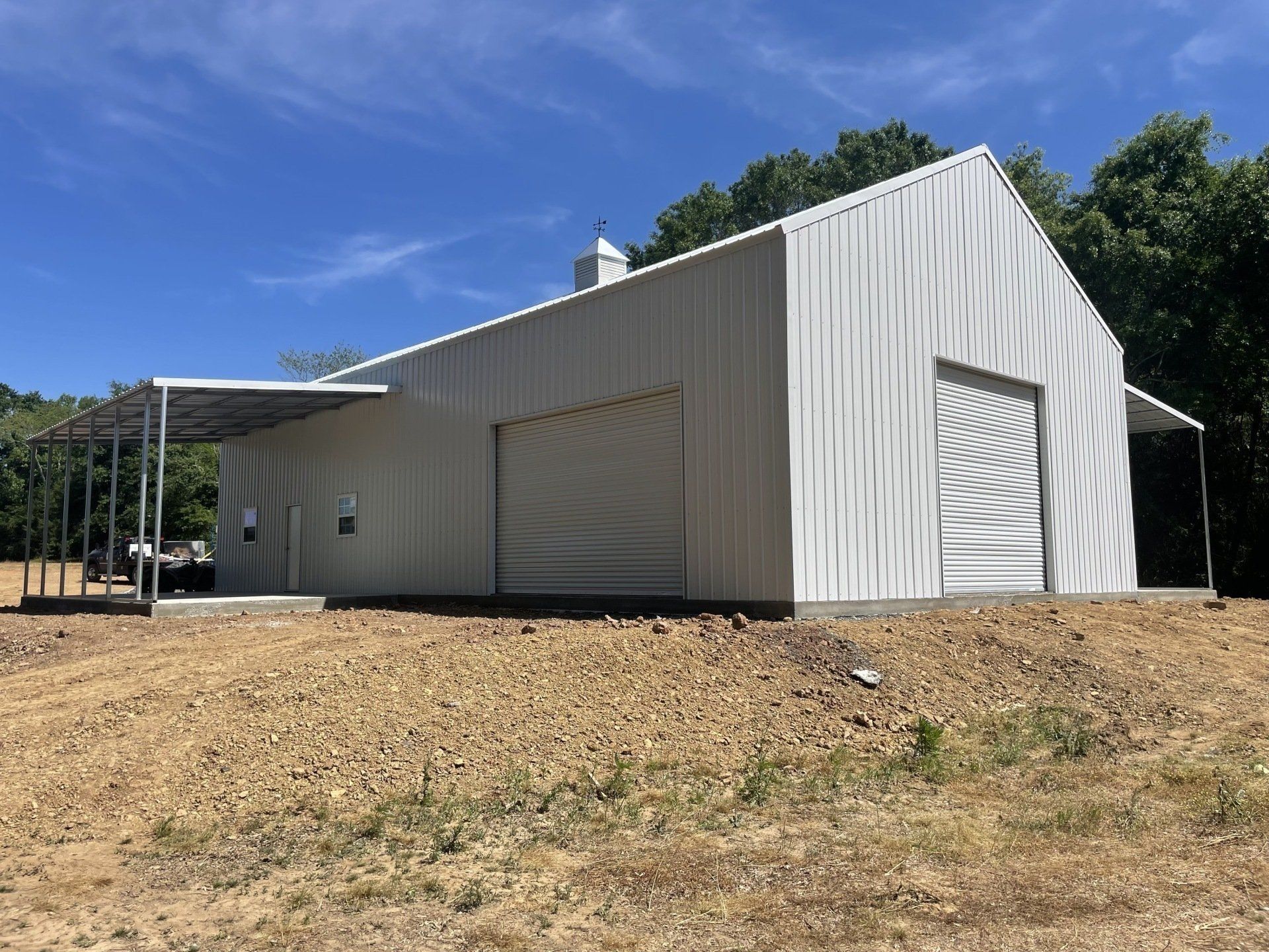 White metal barn with a covered porch on a sunny day.