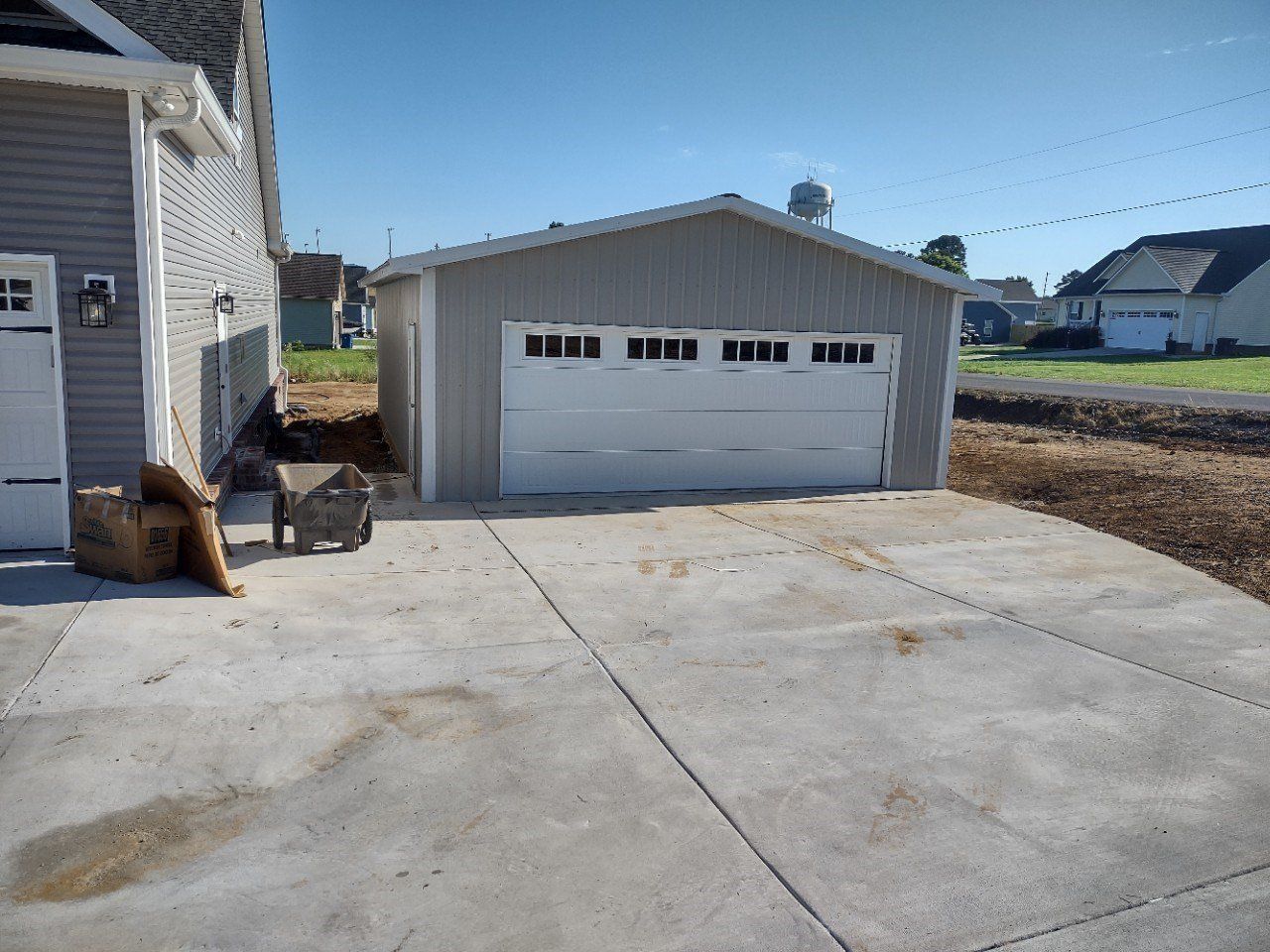 Gray garage with a white garage door, adjacent to a house, on a concrete driveway.