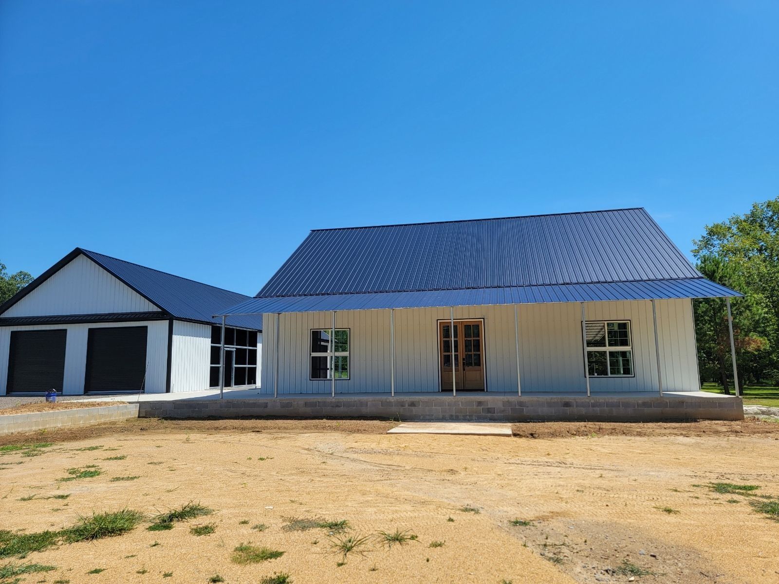 White farmhouse with blue roof and attached garage on a sunny day.
