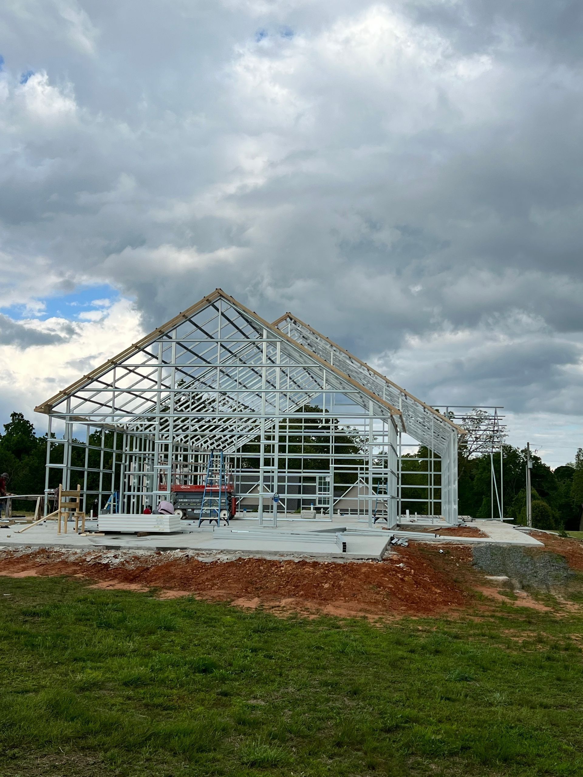 Metal frame of a building under construction against a cloudy sky.