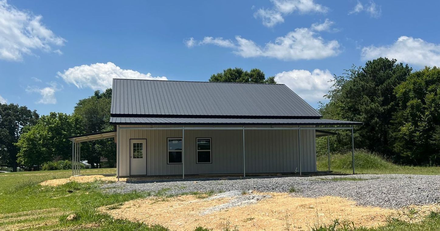 Small, modern house with grey metal roof and porch under a blue sky.