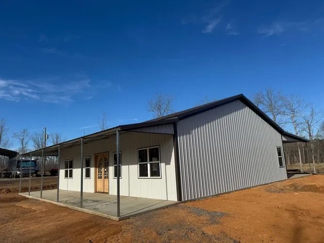 White and corrugated metal building with a porch under a bright blue sky.
