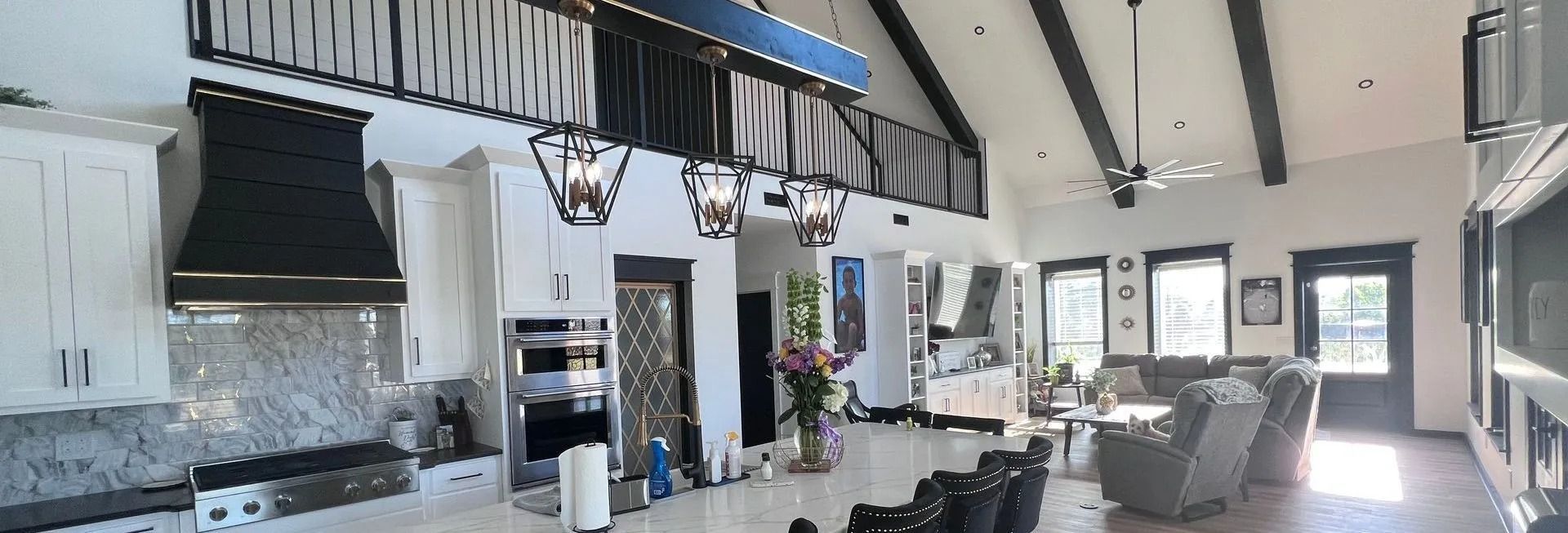 Spacious, open-plan interior with a kitchen, living area, and vaulted ceiling. White walls, black accents, and natural light.