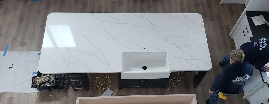 Overhead view of a kitchen island with white countertop, sink, and two workers.