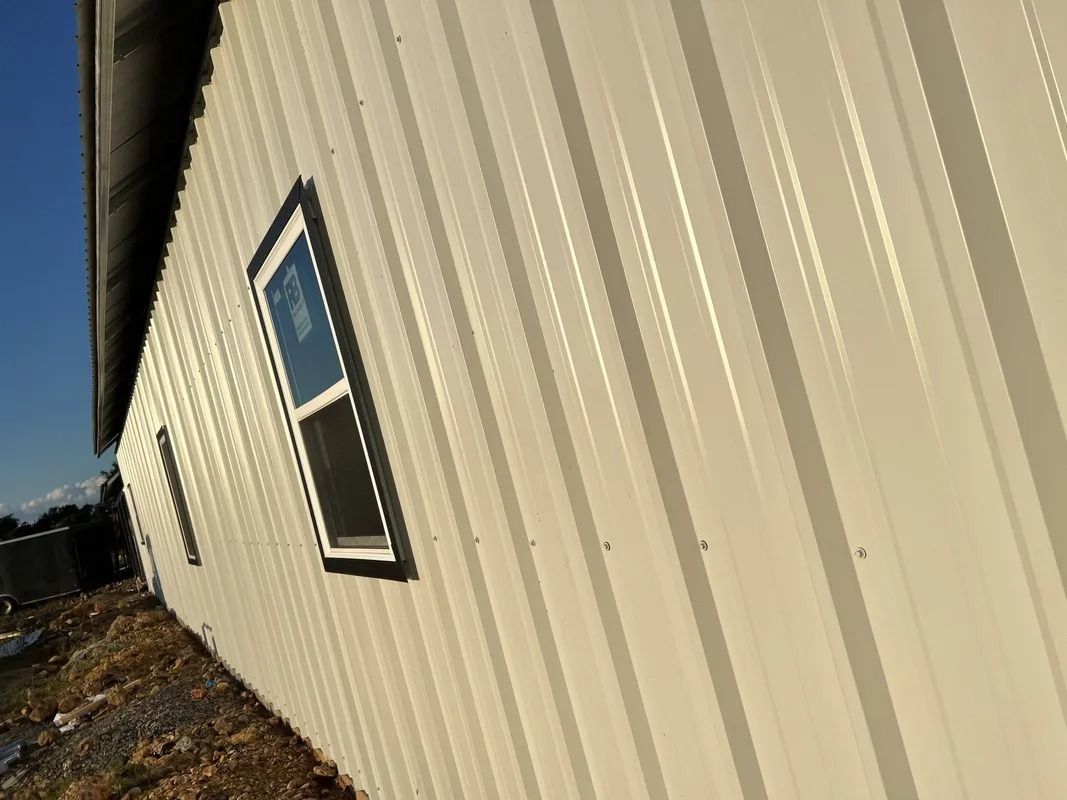 Beige metal siding on a building with a window, against a blue sky.