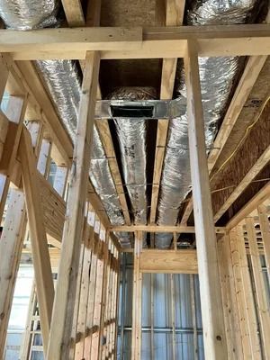 Interior view of new construction: wooden framing, ductwork wrapped in foil, ceiling partially open.