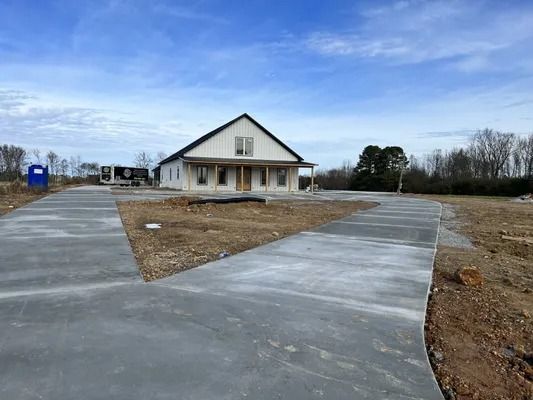 New house under construction with a newly poured concrete driveway under a cloudy sky.