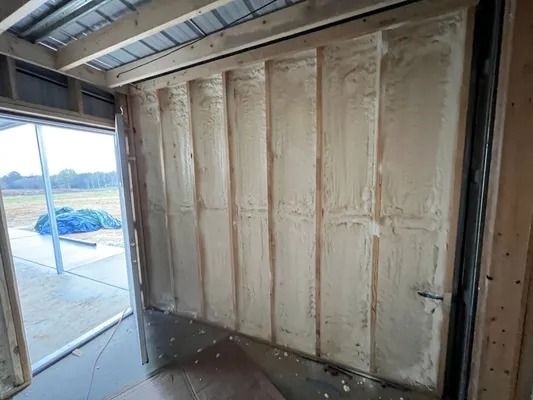 Interior wall with vertical wood beams and spray foam insulation.
