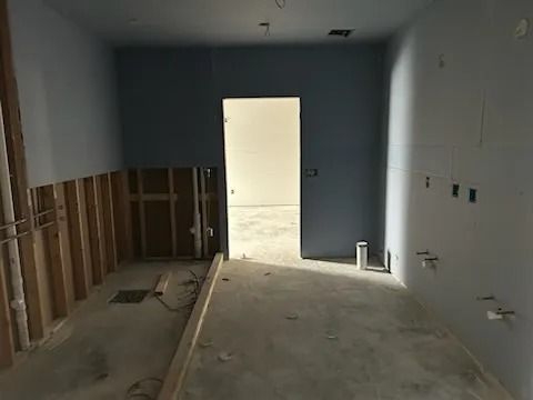 Interior under construction; blue painted walls with exposed studs and doorway leading to another room.