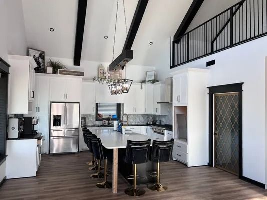 Modern kitchen with white cabinets, black accents, island with seating, and a loft.